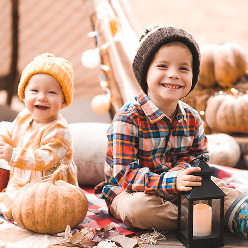 Boy and girl siblings sitting in fall atmosphere smiling.